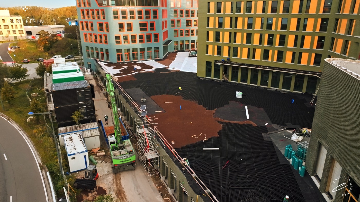 Stedelijk bouwproject in uitvoering met groendakconstructie, omgeven door moderne kleurrijke gevels en bouwmaterialen