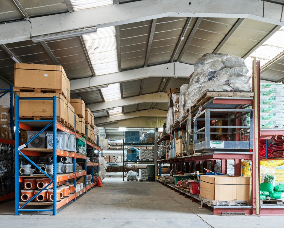 Interieur van een magazijn met stellingen vol bouwmaterialen, gereedschap en producten, gereed voor projectuitvoering.