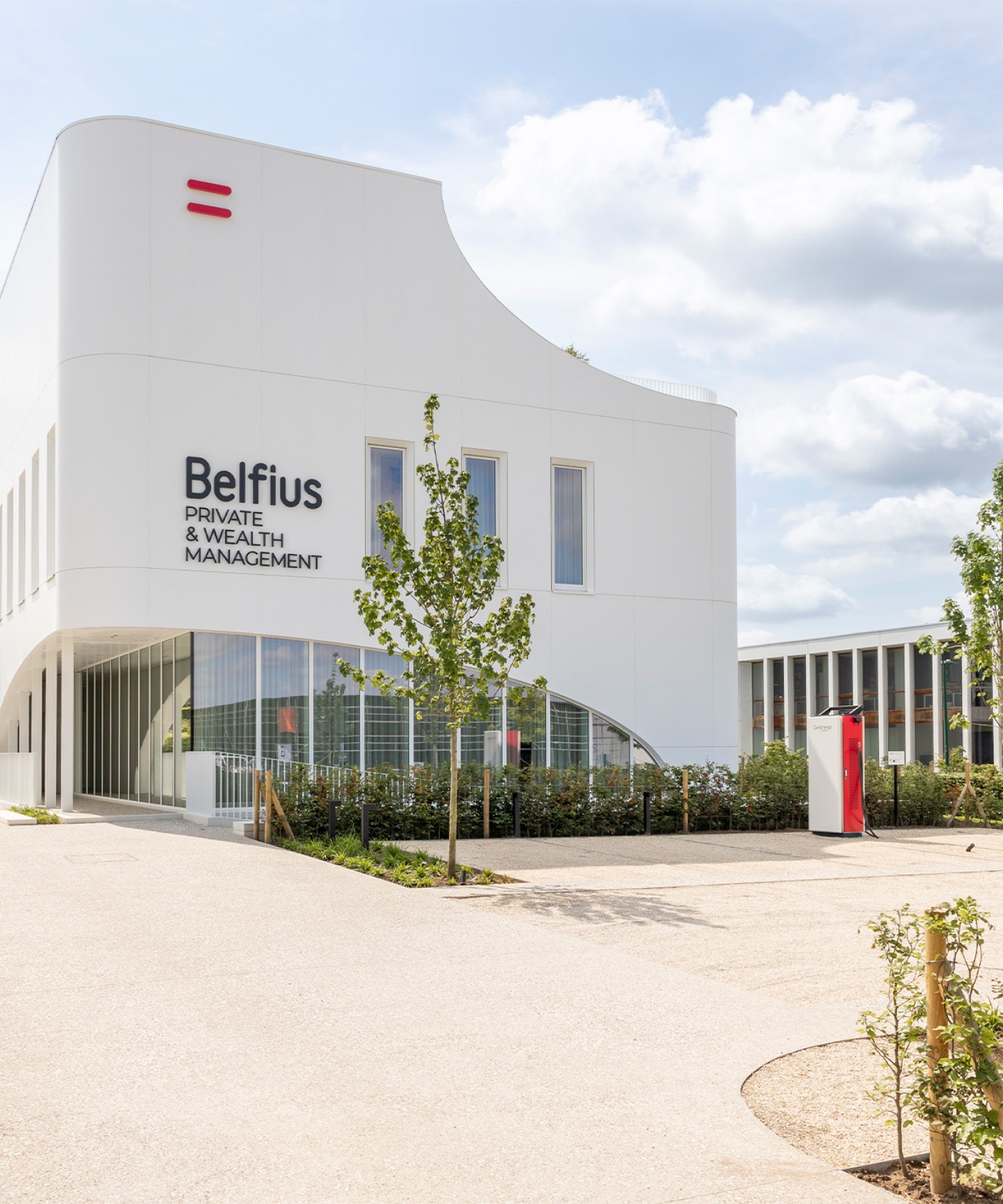 Voorzijde van het Belfius Private &amp; Wealth House in Kortrijk met moderne witte architectuur en groenaanleg
