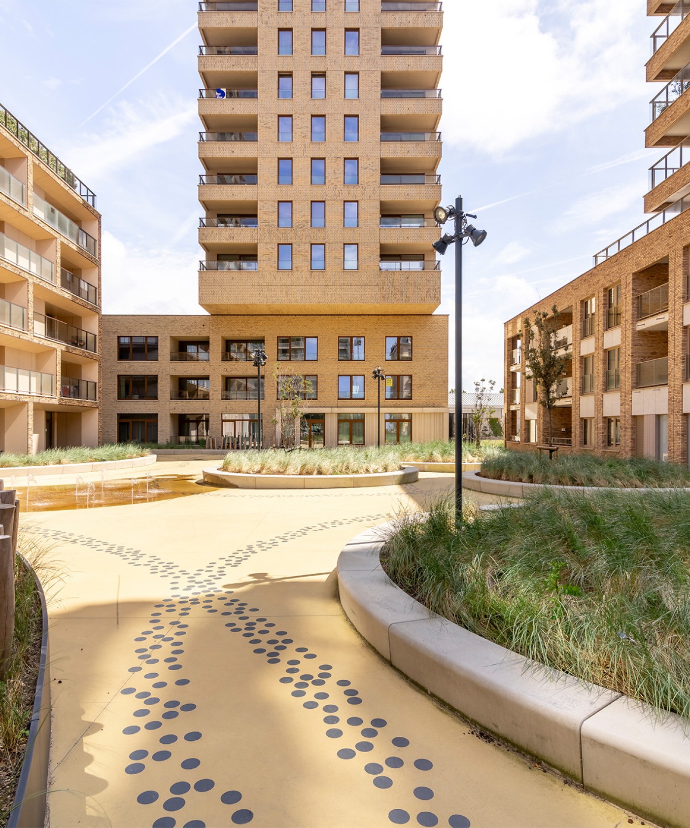 Ruime binnentuin van O'Sea in Oostende met graszones, een fontein en zitbanken, omringd door moderne appartementen