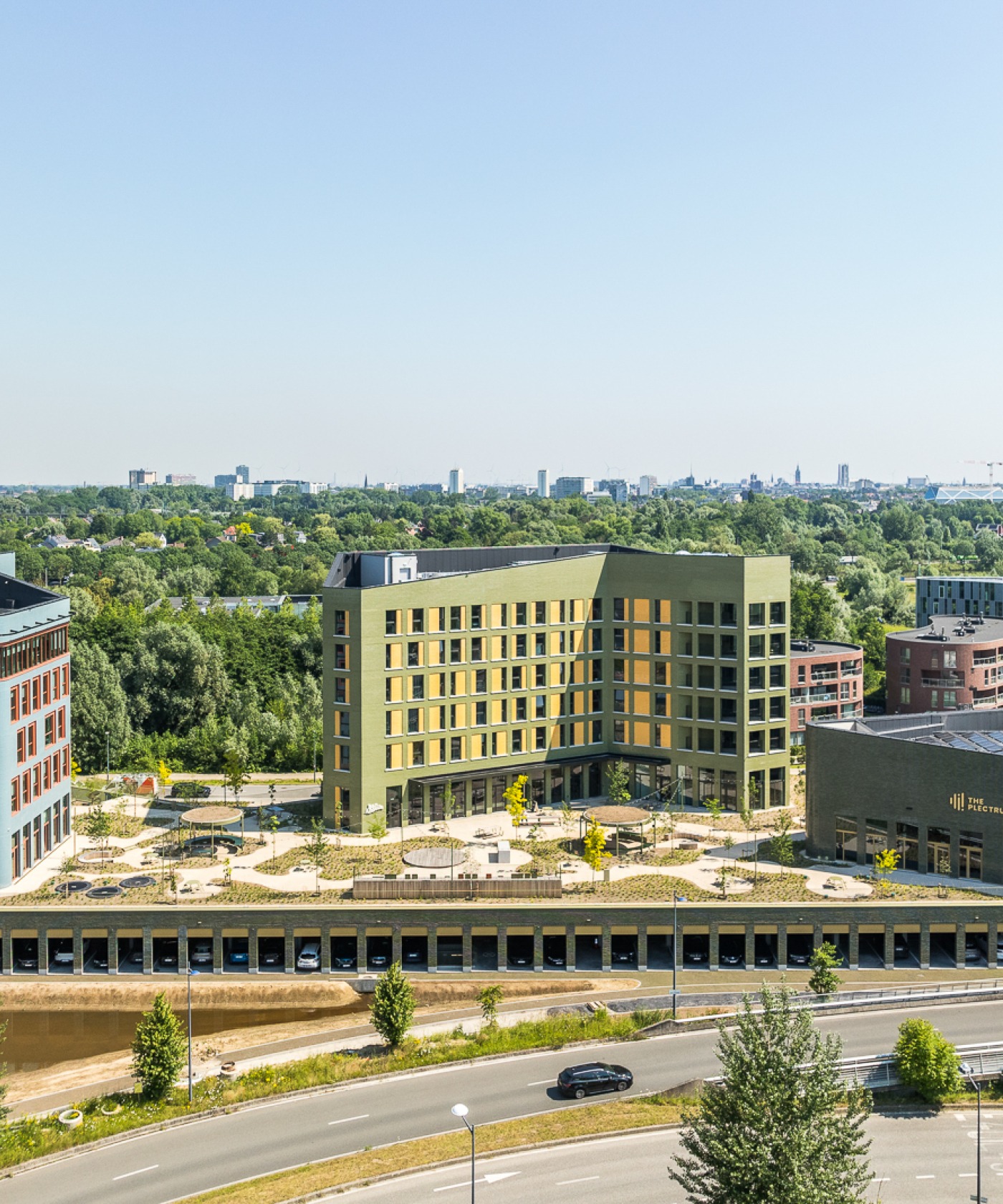 Moderne groene daktuin met bomen en zitplekken op een gebouw van Upoffiz in Gent, met uitzicht op een stedelijk landschap