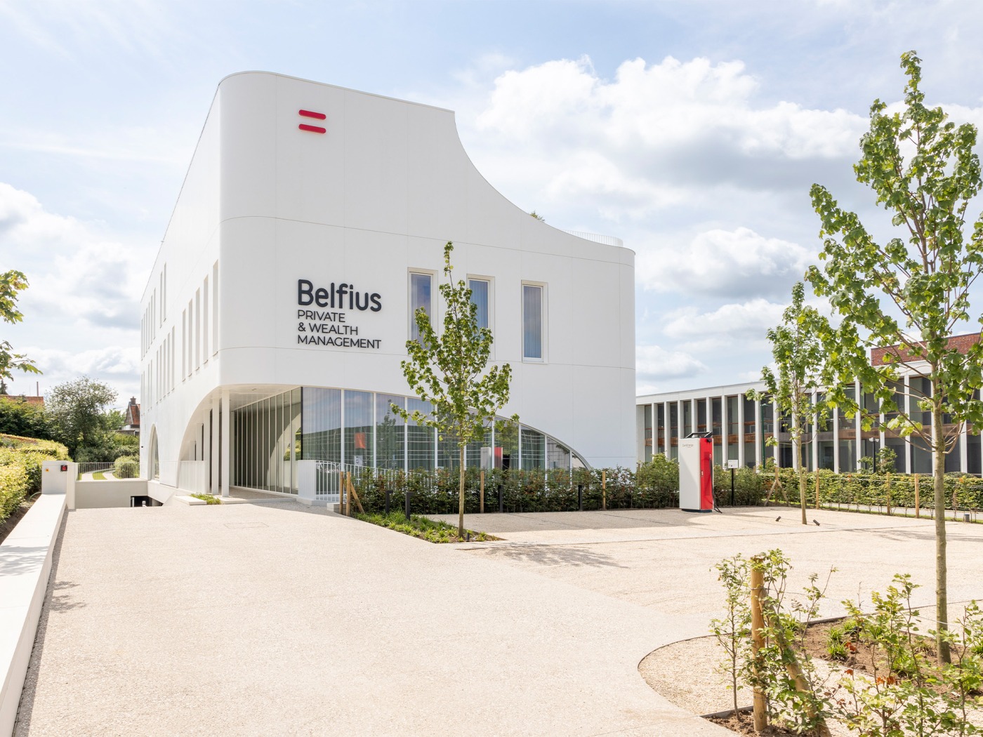 Voorzijde van het Belfius Private &amp; Wealth House in Kortrijk met moderne witte architectuur en groenaanleg