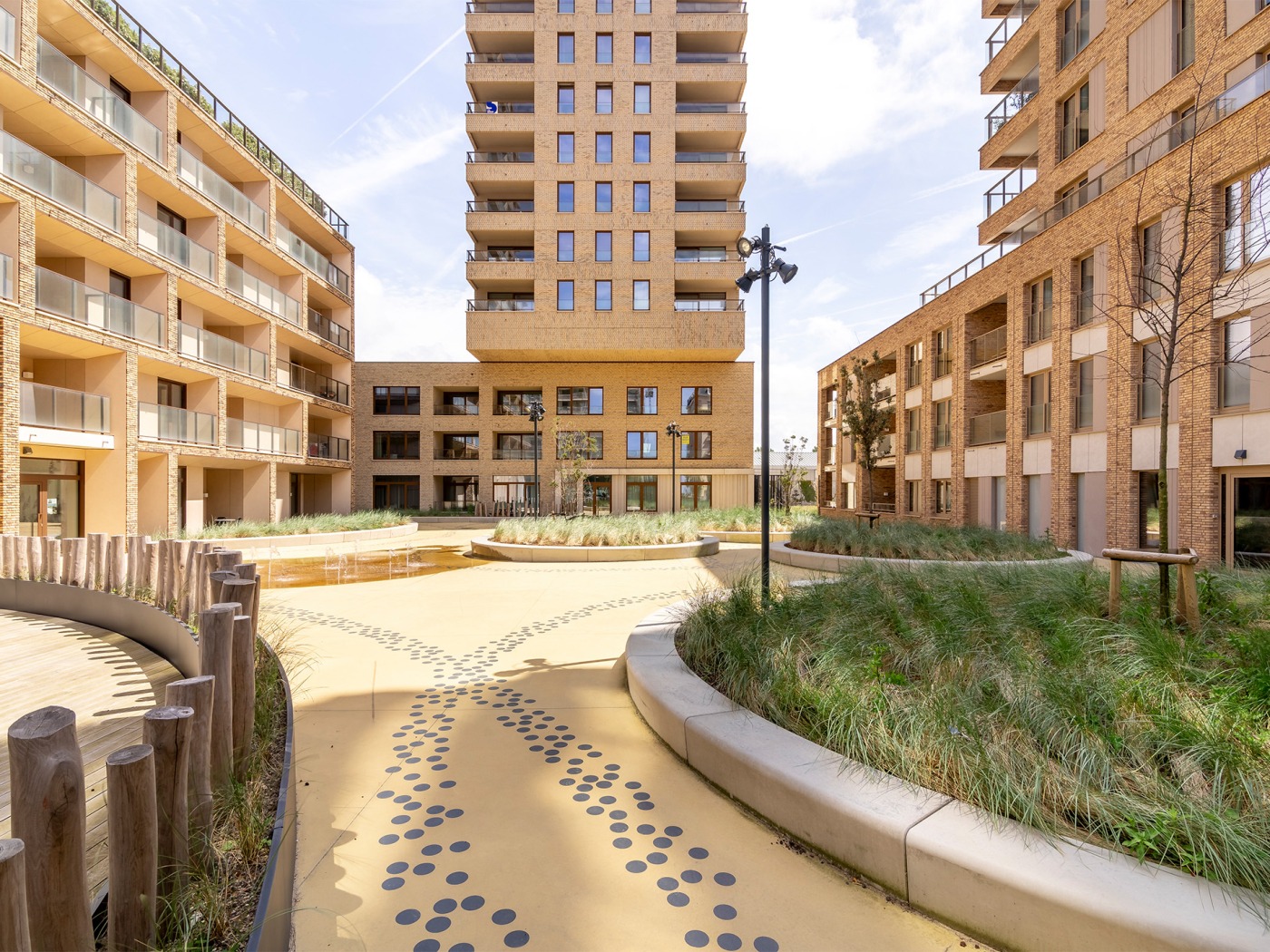 Ruime binnentuin van O'Sea in Oostende met graszones, een fontein en zitbanken, omringd door moderne appartementen
