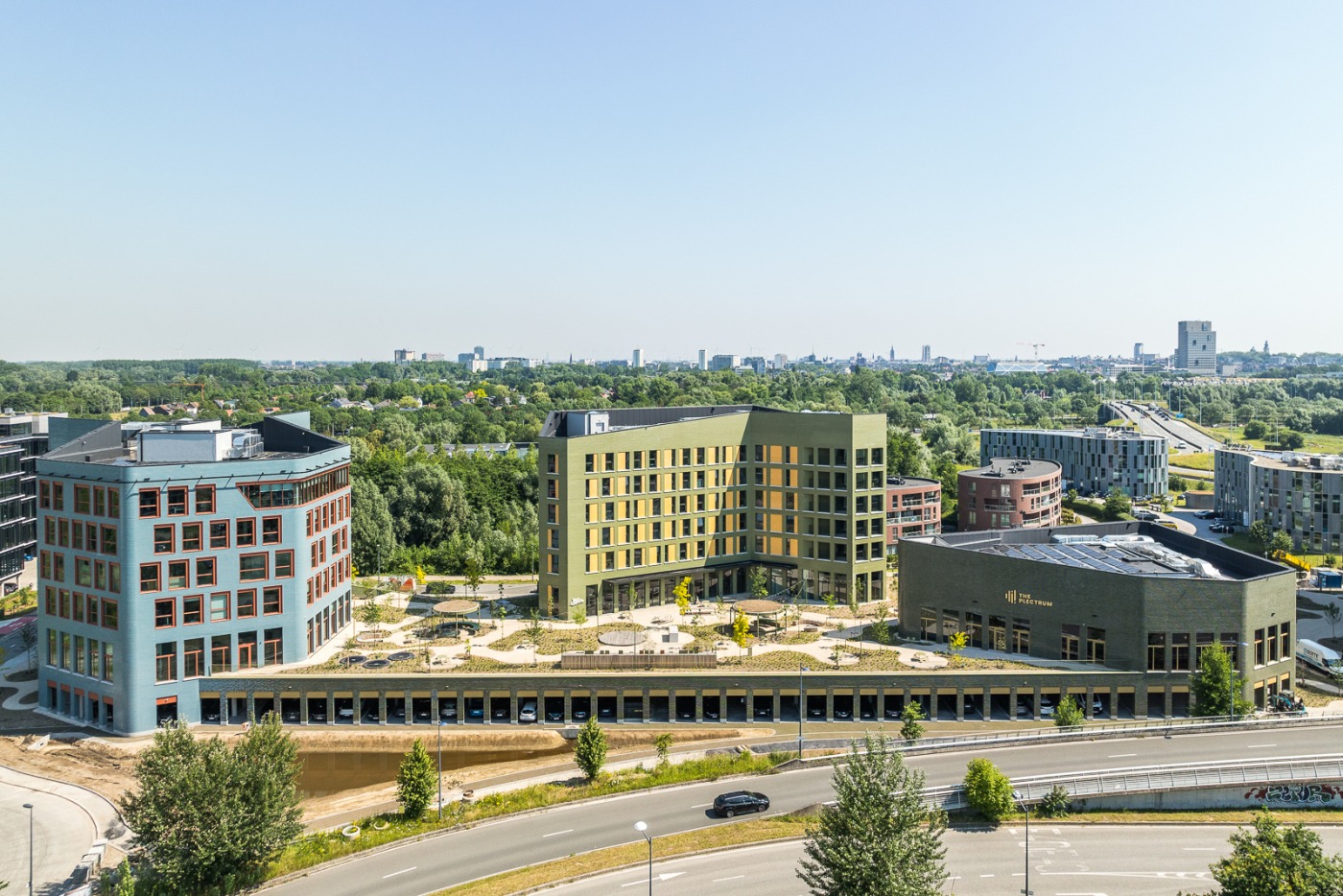 Moderne groene daktuin met bomen en zitplekken op een gebouw van Upoffiz in Gent, met uitzicht op een stedelijk landschap